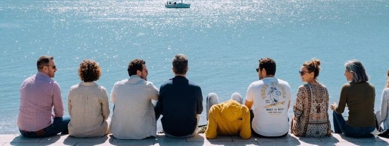 Grupo de personas sentadas mirando al mar